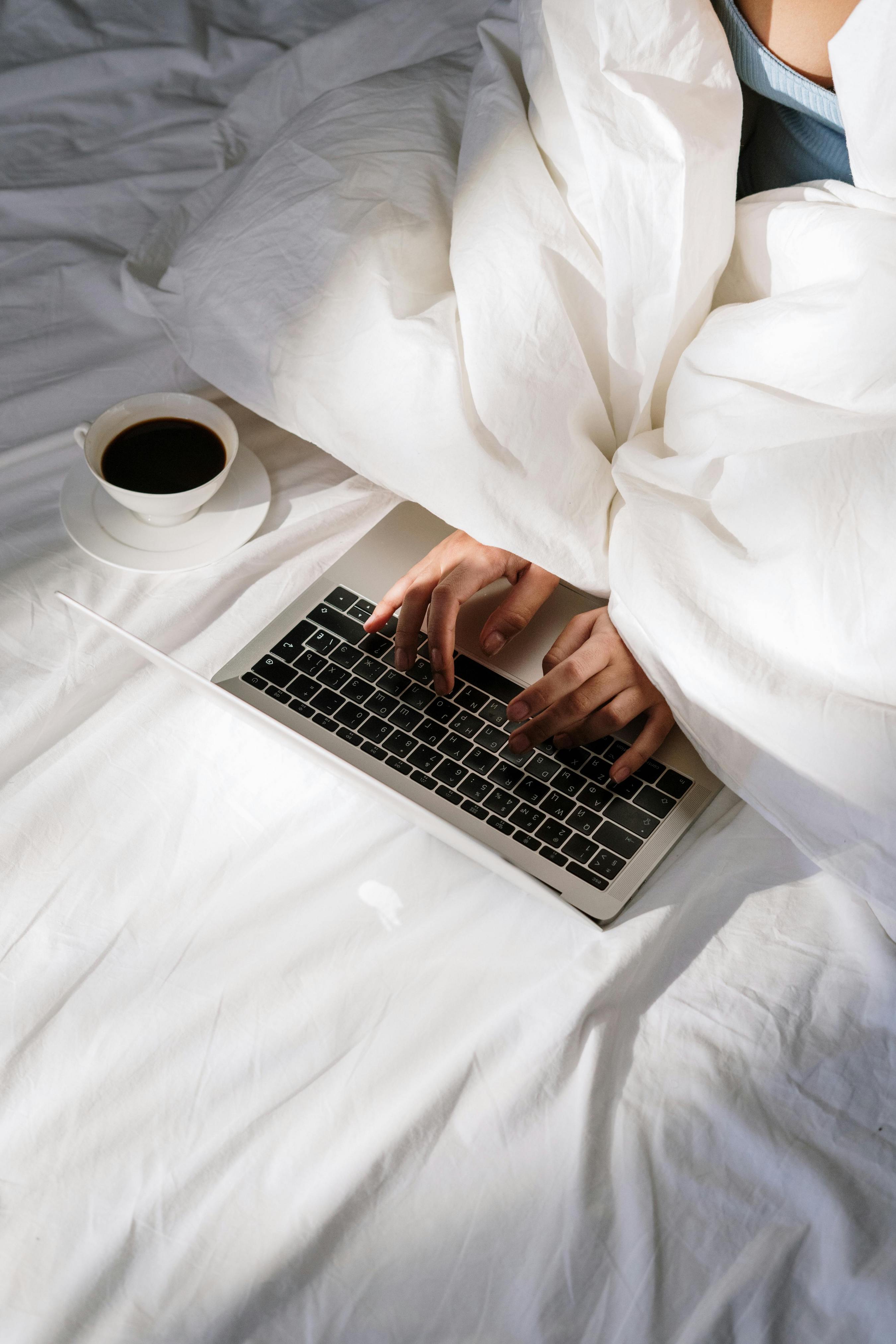 laptop on a bed with coffee